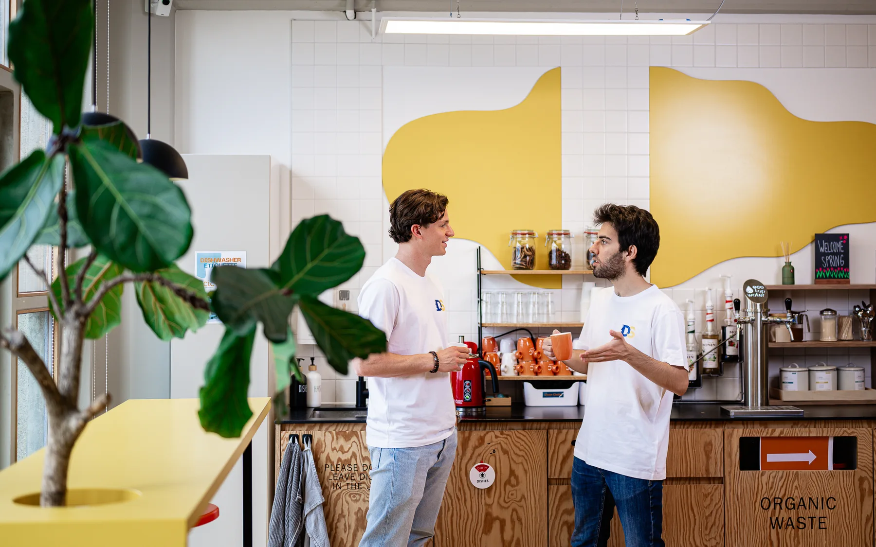 Two colleagues talking over coffee at the NewData office